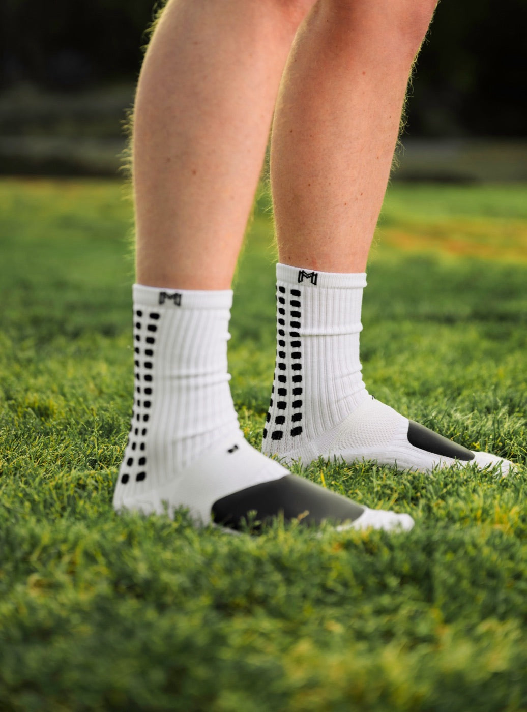 White MediCaptain padded grip socks on grass, with the black ShockPad over the top of each foot