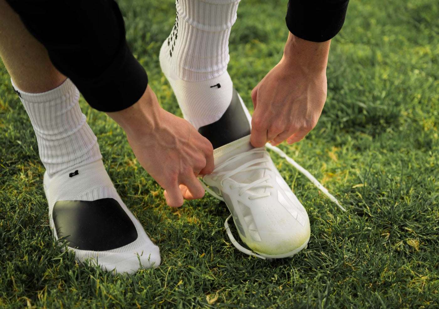 Player pulling a white cleat on over a MediCaptain padded grip sock