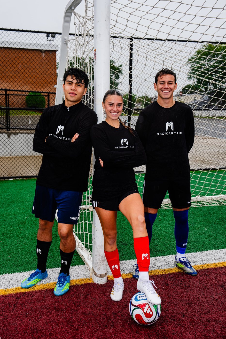 Three players in MediCaptain kit by the goal wearing black, red and blue MediCaptain socks